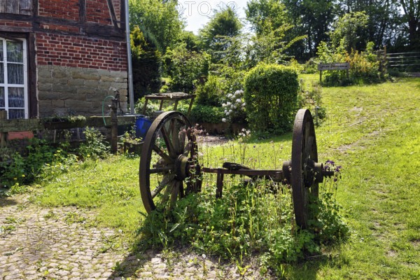 Rusted metal wheels on an axle, decoration in a garden, country inn in summer, Rischenau, LÃ¼gde, Weserbergland, North Rhine-Westphalia, Germany