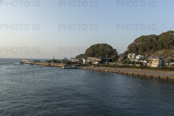 Residential houses on the coast in the evening light and mountain landscape in the harbour of Hamakanaya, Futtsu, Chiba Prefecture, Japan