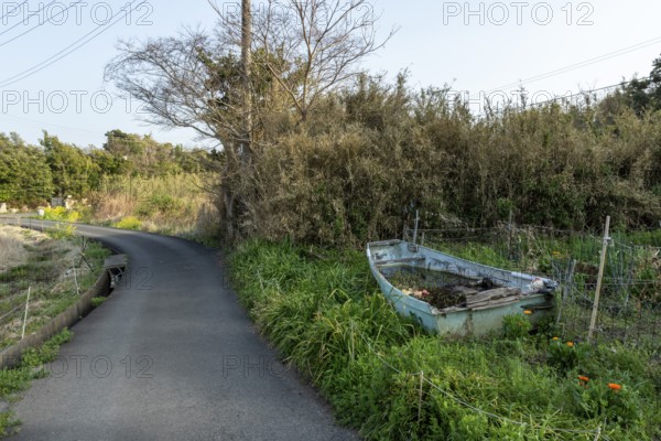 Old wooden boat on the side of a road in a rural landscape in the evening light, Hota, Kyonan, Chiba Prefecture, Japan