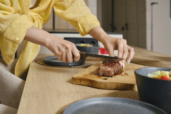 A person skillfully slices a perfectly cooked duck breast on a wooden cutting board in a stylish kitchen. Fresh vegetables sit in bowls nearby, indicating a nutritious meal being prepared