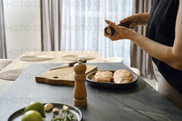 In a contemporary kitchen, a person is seasoning duck fillets with pepper while preparing dinner