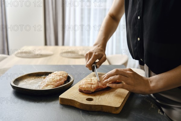 A person skillfully slices fresh duck fillets on a wooden cutting board in a modern kitchen