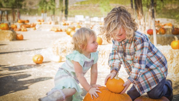 Young brother and sister playing in a rustic ranch setting at the pumpkin patch