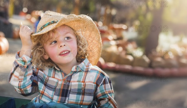 Cute young boy wearing cowboy hat at pumpkin patch farm
