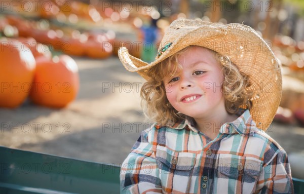 Cute young boy wearing cowboy hat at pumpkin patch farm