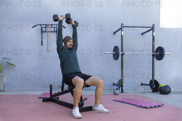 Focused athlete lifting dumbbells while seated on a bench in an outdoor gym, demonstrating strength and unwavering dedication to fitness and a healthy lifestyle