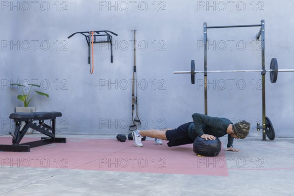 Young athlete performing push-ups with hands on a medicine ball in an outdoor gym, showcasing strength and fitness while embracing an active and healthy lifestyle