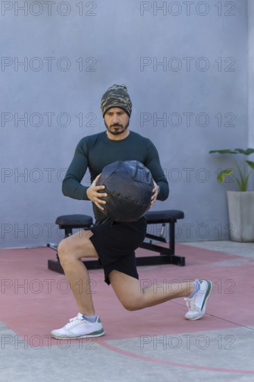 Athlete performing lunges while gripping a medicine ball, showcasing strength and balance during an invigorating outdoor workout, embodying a commitment to fitness and wellness