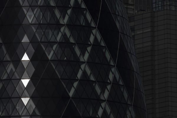 The Gherkin skyscraper building close up of window details with sunlight illuminating three triangle windows, City of London, England, United Kingdom