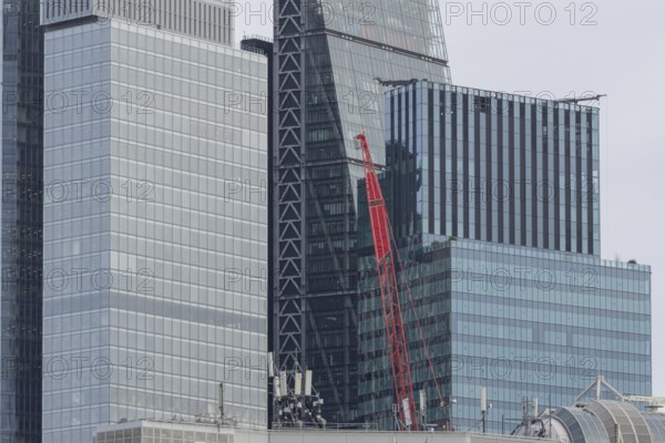 Mechanical red crane on a building in front of skyscrapers, City of London, England, United Kingdom