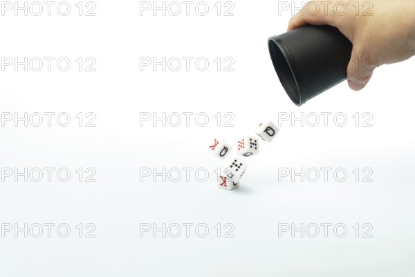 Poker dice falling from a black cup held by a hand, symbolizing risk, chance, and the thrill of gambling