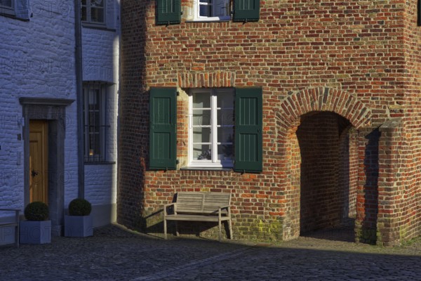 Red brick house with green shutters and bench in the shade, DÃ¼sseldorf