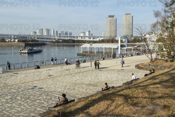 Strollers on the promenade and futuristic Tokyo Cruise Water Bus Queen Emeraldas, excursion boat for harbour cruises in Tokyo Bay, Odaiba, Minato City, Tokyo, Japan
