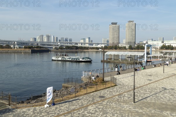Strollers on the promenade and futuristic Tokyo Cruise Water Bus Queen Emeraldas, excursion boat for harbour cruises in Tokyo Bay, Odaiba, Minato City, Tokyo, Japan