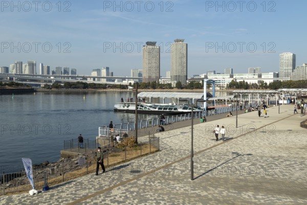 Strollers on the promenade and futuristic Tokyo Cruise Water Bus Queen Emeraldas, excursion boat for harbour cruises in Tokyo Bay, Odaiba, Minato City, Tokyo, Japan