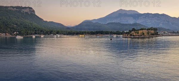 Seascape sunset panorama over the Mediterranean Sea near Kemer, Turkey. Panoramic view to the moonlight beach at dusk and boats cruising across the calm waters