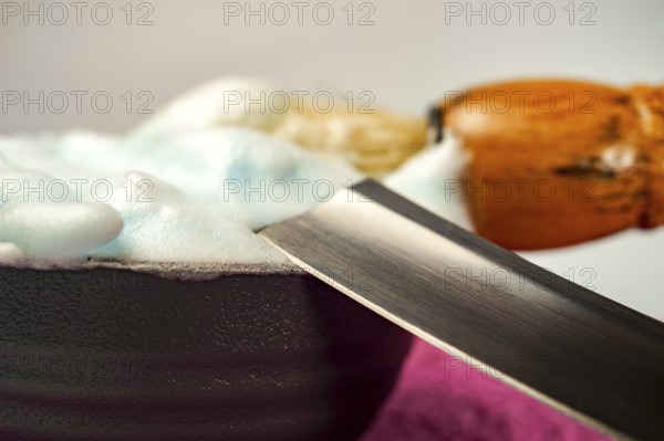 Shaving cream in bowl with straight razor and shaving brush, ready for barber to prepare customer for a shave
