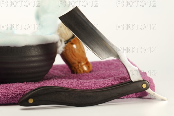 Shaving accessories including a straight razor, shaving brush, and bowl filled with soap foam, evoke a sense of traditional grooming and relaxation