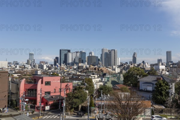 Modern architecture, view over the rooftops of the city to the glass facades of skyscrapers against a blue sky, skyline of Shinjuku, Tokyo, Chiba, Japan