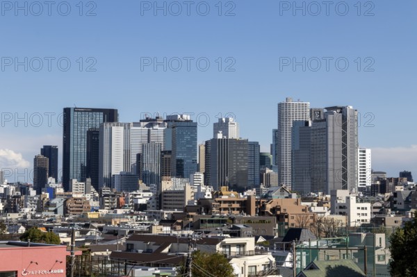 Modern architecture, view over the rooftops of the city to the glass facades of skyscrapers against a blue sky, skyline of Shinjuku, Tokyo, Chiba, Japan