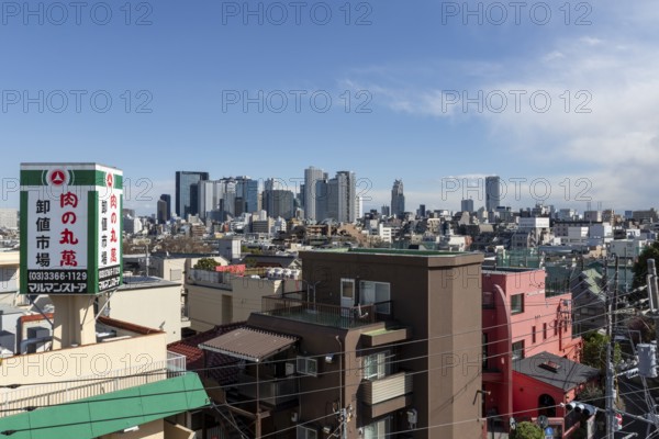 Modern architecture, view over the rooftops of the city to the glass facades of skyscrapers against a blue sky, skyline of Shinjuku, Tokyo, Chiba, Japan