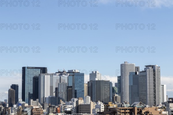 Modern architecture, view over the rooftops of the city to the glass facades of skyscrapers against a blue sky, skyline of Shinjuku, Tokyo, Chiba, Japan