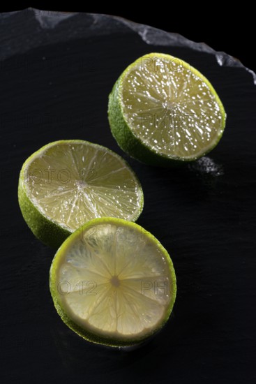 Three lime slices on a black stone plate