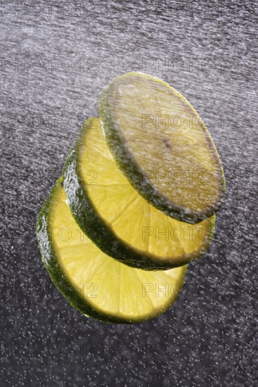 Three lime slices with drops of water