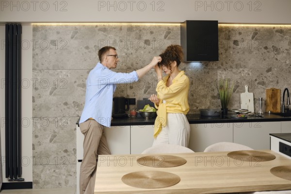 Couple enjoying a playful moment in a modern kitchen while preparing a meal together