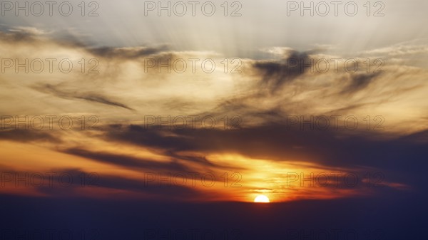 Sunset behind cloud cover, sunbeams, Oia, Thira, Santorini, Cyclades, Greece