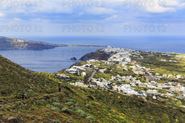 Coastline with view of the village of Oia, hiker on hiking trail from Fira to Oia, Thira, Santorini, Cyclades, Greece