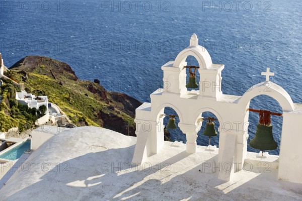 White bell tower of an orthodox church overlooking the sea, coastline, Oia, Santorini, Cyclades, Aegean Sea, Greece