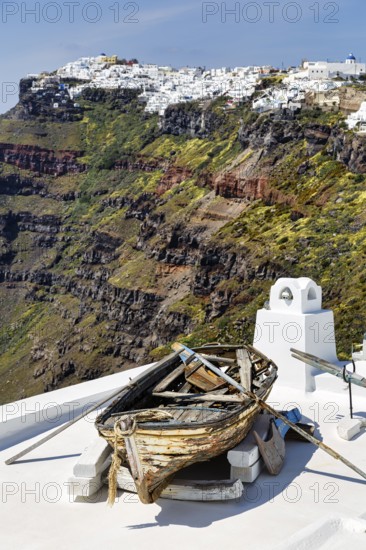 Rowing boat, wreck, decoration on a house roof, steep coast, edge of the caldera, Firostefani, Santorini, Greece
