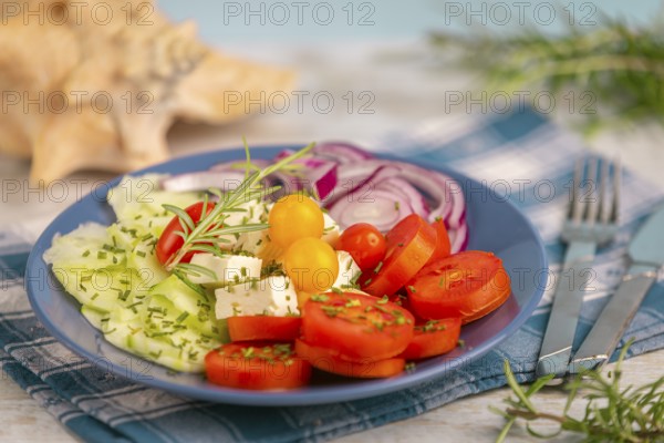 Mediterranean vegetable platter with tomatoes, cucumber, onion and feta on a chequered cloth with cutlery