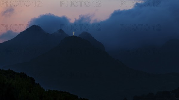 Illuminated steel cross on the summit of Monte Mar di Capanna, above Porto Azzurro, night shot, Elba Island, Tuscan Archipelago National Park, Tuscany, Italy