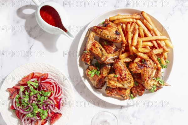 Delicious barbecue chicken wings, with French fries, salad and a refreshing drink, at a cozy table, there are no people