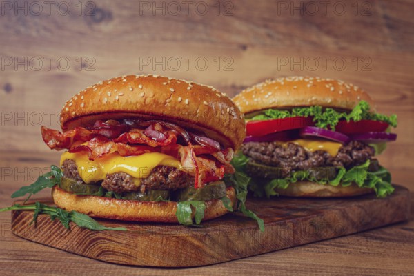Two burgers with beef patty, fried bacon, cheddar cheese, tomatoes, homemade, no people