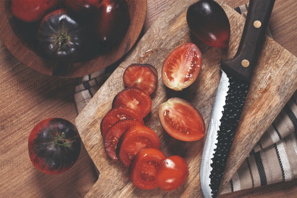 Sliced tomatoes, Black Beauty variety, on a cutting board, top view, on the kitchen table