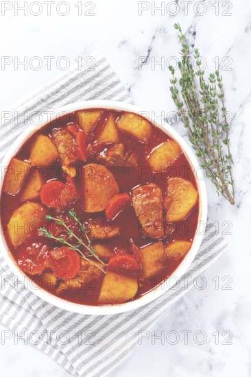 Meat goulash with potatoes and carrots, sweet peppers, in a saucepan, top view, traditional Hungarian soup, homemade, no people