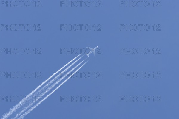 Airbus A340-300 jet aircraft of Lufthansa airlines in flight in a blue sky with vapour trails or contrails behind, England, United Kingdom