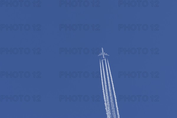 Airbus A340-300 jet aircraft of Lufthansa airlines in flight in a blue sky with vapour trails or contrails behind, England, United Kingdom