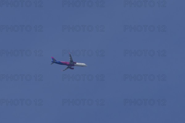 Airbus A321 jet aircraft of Wizz Air airlines in flight in a blue sky, England, United Kingdom