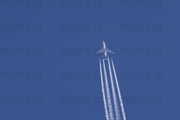 Airbus A340-300 jet aircraft of Lufthansa airlines in flight in a blue sky with vapour trails or contrails behind, England, United Kingdom