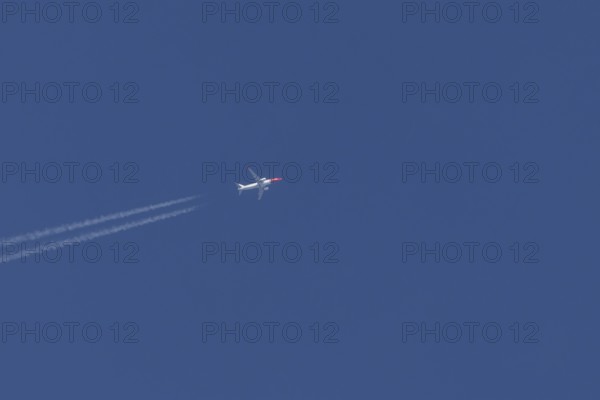 Boeing 737 jet passenger aircraft of Norwegian Air airlines in flight in a blue sky with vapour trails or contrails behind, England, United Kingdom