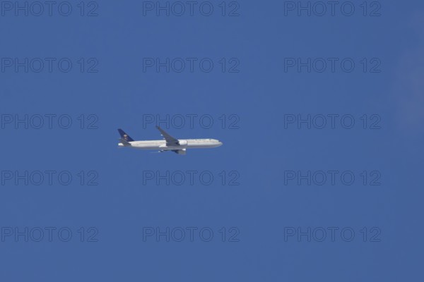 Boeing 777 jet passenger aircraft of Saudi airlines in flight in a blue sky, England, United Kingdom