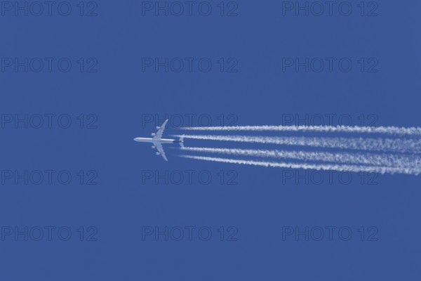 Airbus A340-300 jet aircraft of Lufthansa airlines in flight in a blue sky with vapour trails or contrails behind, England, United Kingdom