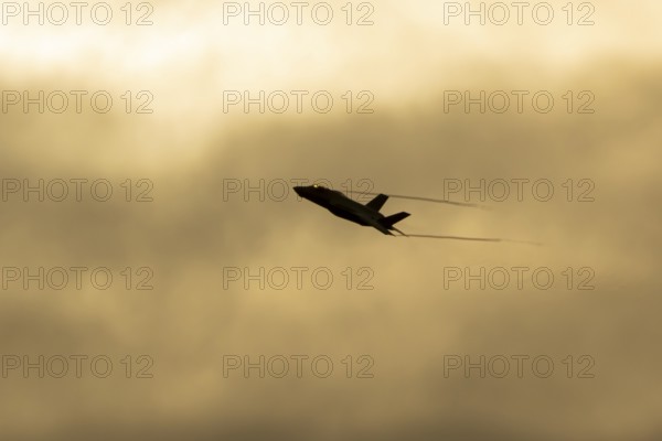 Lockheed Martin F-35 Lightning II fighter military aircraft of the United States air force USAF silhouette in flight at sunset at RAF Lakenheath airbase, Suffolk, England, United Kingdom