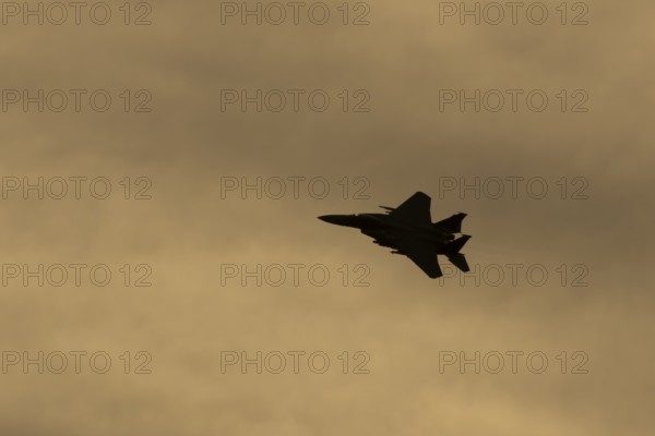 McDonnell Douglas F-15E Strike Eagle fighter military aircraft of the United States air force USAF in flight silhouette at sunset at RAF Lakenheath airbase, Suffolk, England, United Kingdom