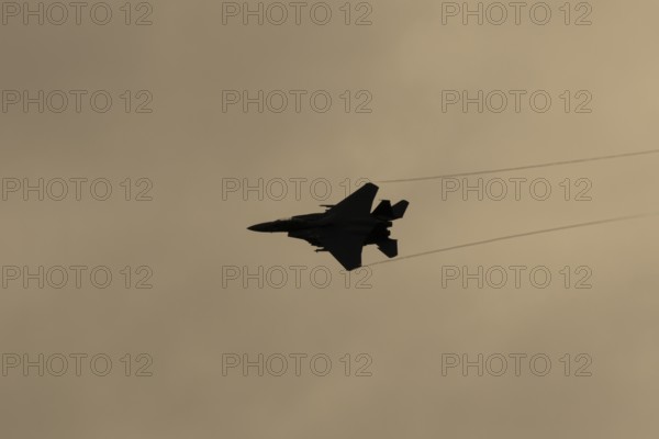 McDonnell Douglas F-15E Strike Eagle fighter military aircraft of the United States air force USAF in flight silhouette at sunset at RAF Lakenheath airbase, Suffolk, England, United Kingdom