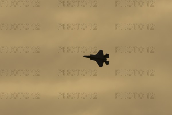 Lockheed Martin F-35 Lightning II fighter military aircraft of the United States air force USAF silhouette in flight at sunset at RAF Lakenheath airbase, Suffolk, England, United Kingdom